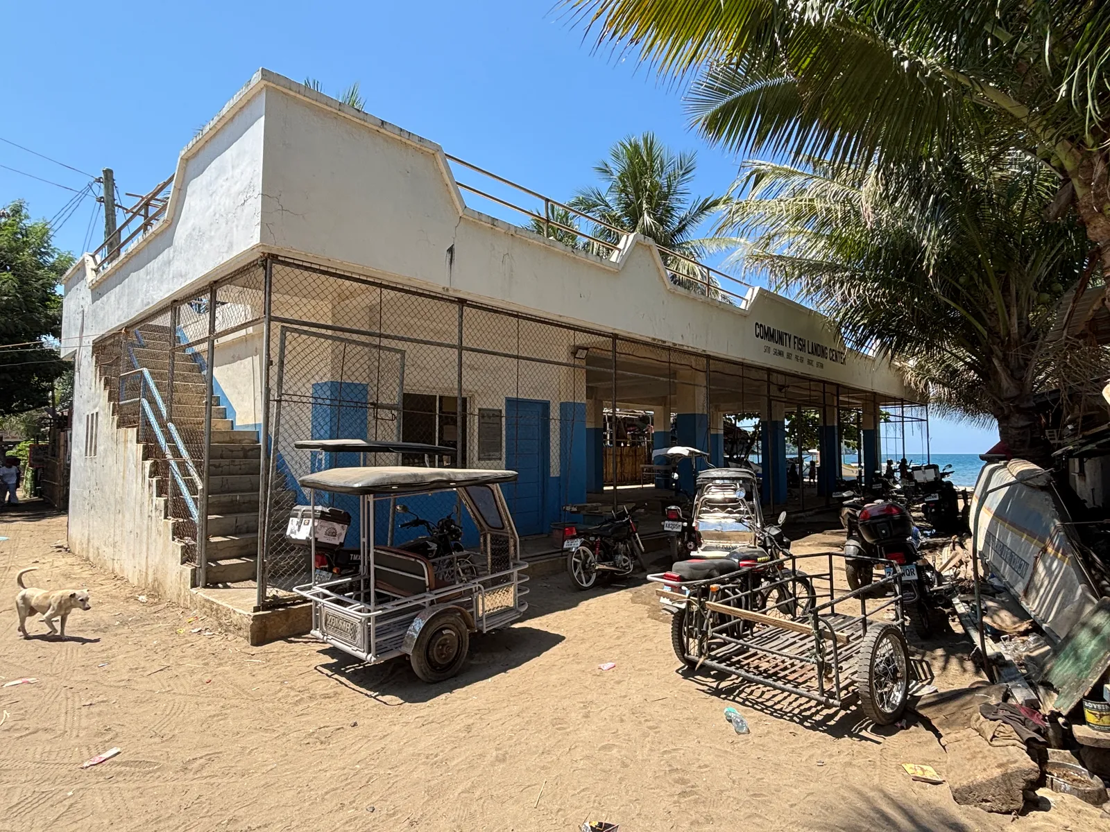 A community fish landing centre by the shore with tricycles parked outside